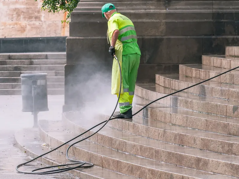 Worker pressure washing outdoor stone steps